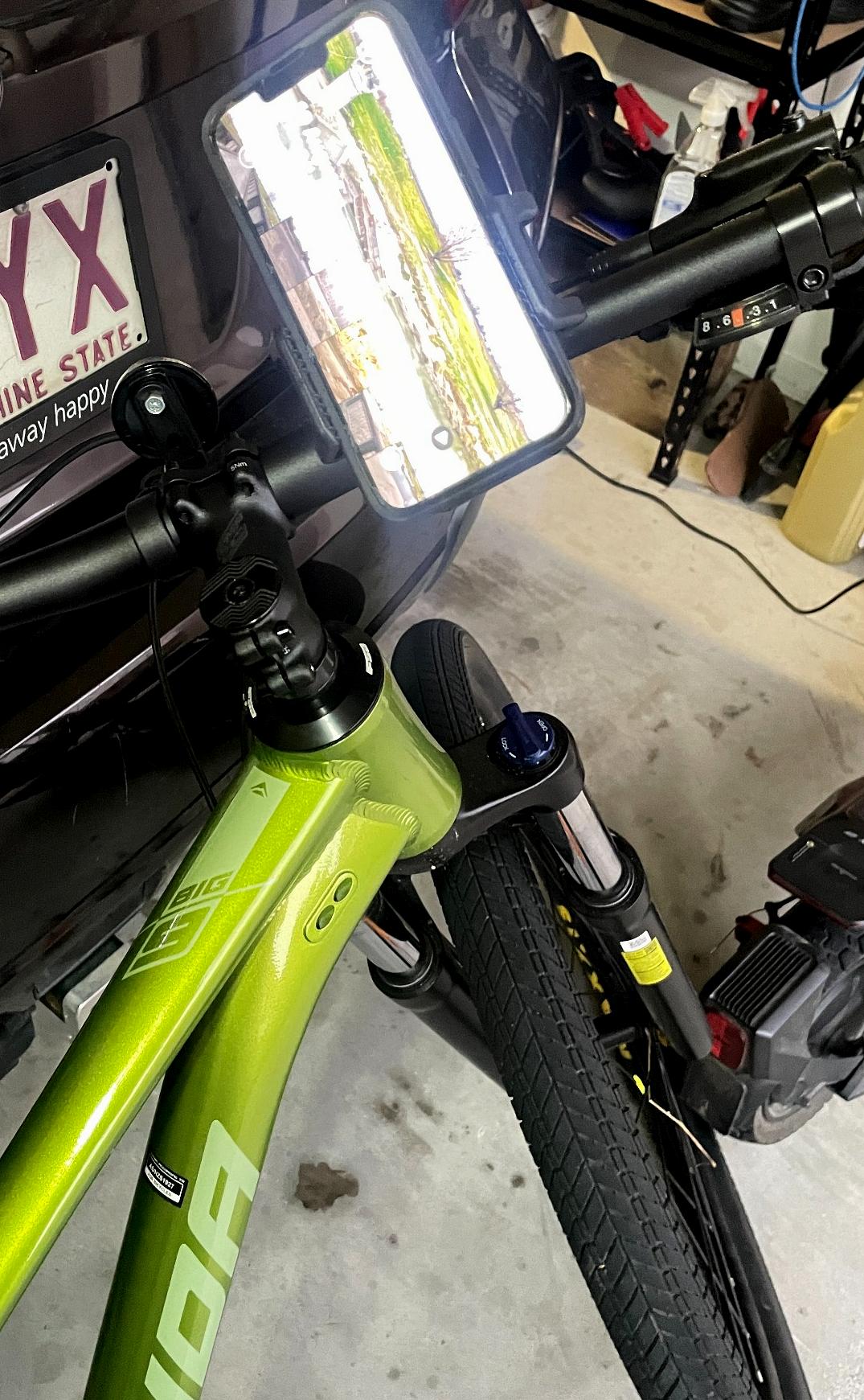 Close-up of a green bicycle with a license plate holder attached, in an indoor setting.